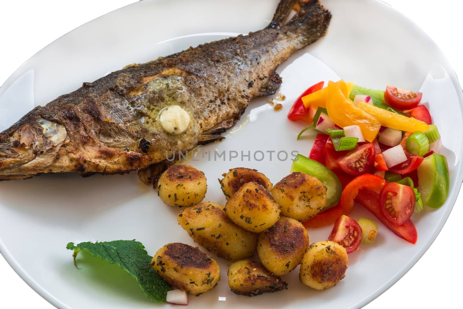 Roasted trout on white plate with lemon and roasted potatoes.