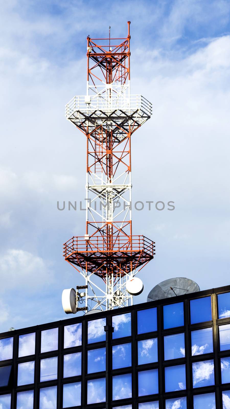 Antena on the building that reflects sky and clouds