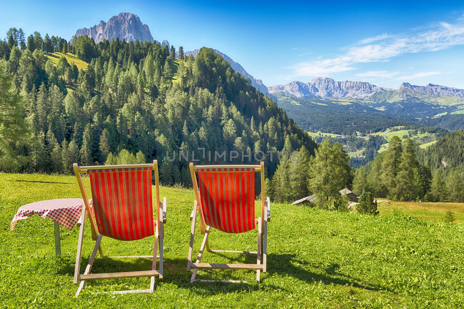 deck chairs and table on the lawn overlooking the mountains and the valley in summer