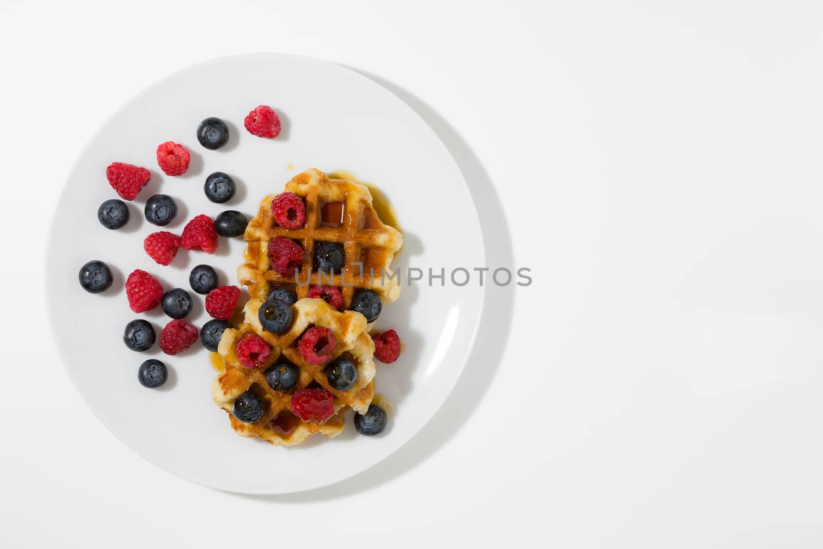 Waffles with berries and maple syrup seen from above