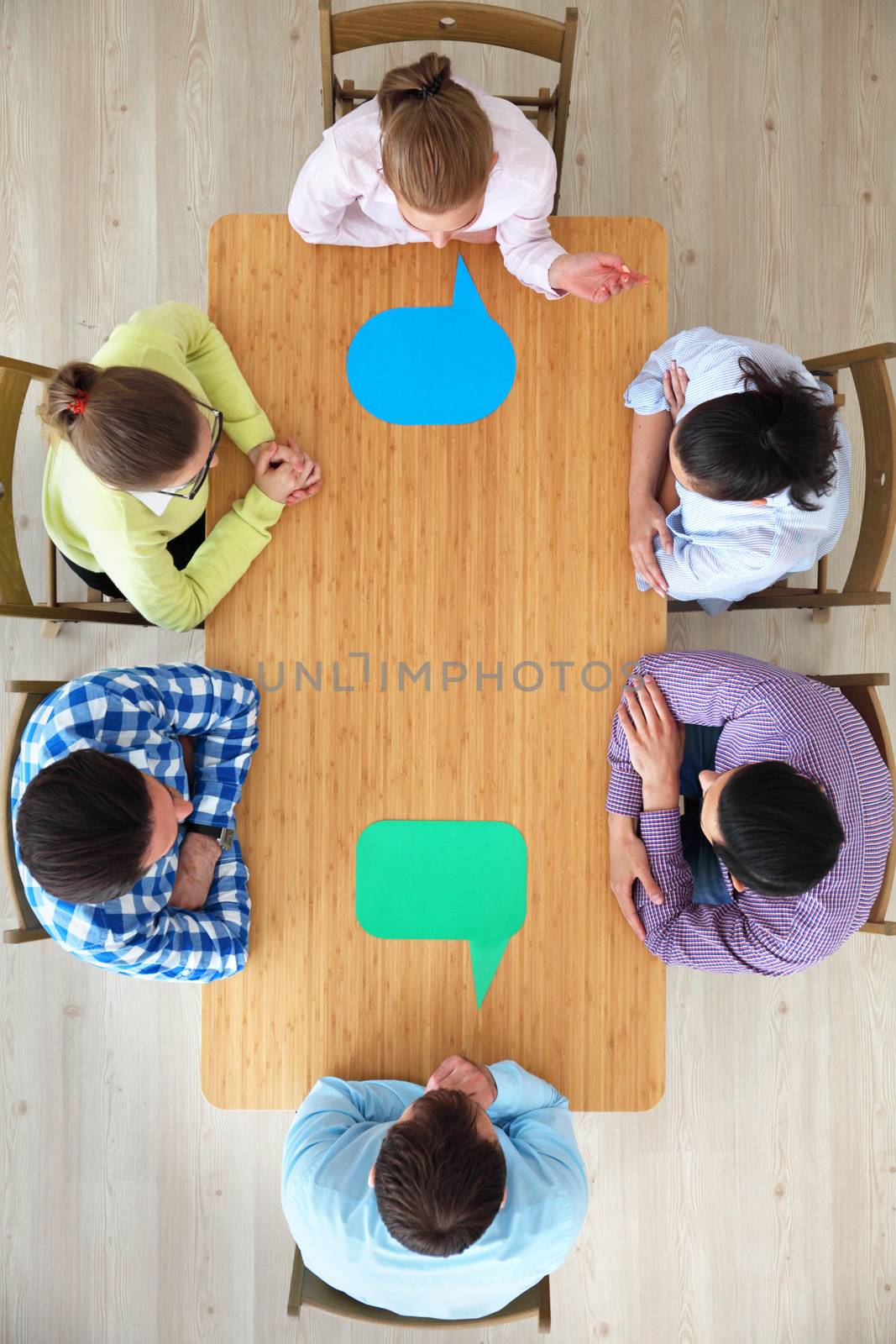 Hipster business teamwork brainstorming planning meeting concept, people sitting around the table with color paper shaped like dialog cloud