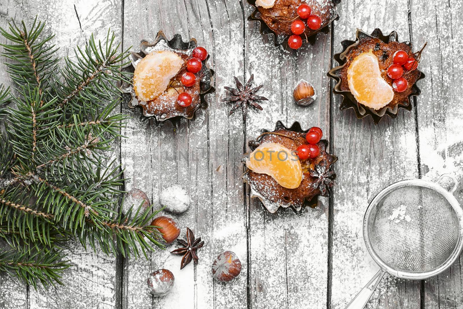 Chocolate Christmas muffins,sieve the powder on background with branch of Christmas tree