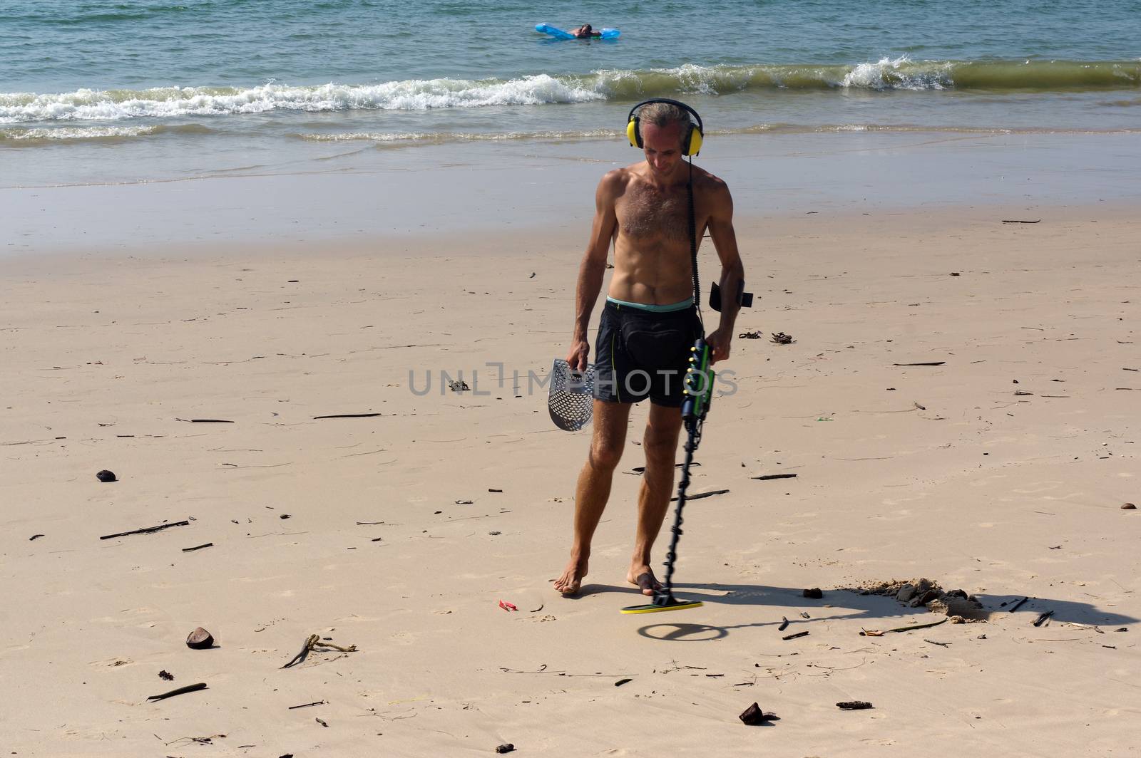 Treasure hunter with Metal detector on the beach by evolutionnow