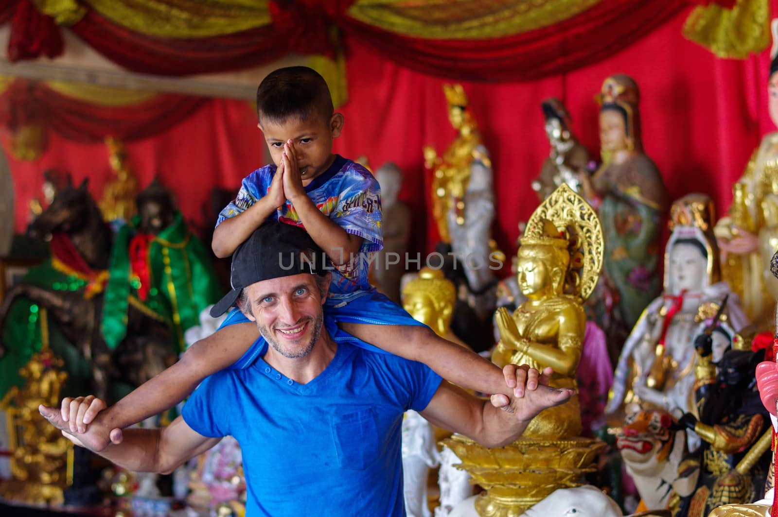 a pretty boy enjoying riding on man's back in a temple, Phuket
