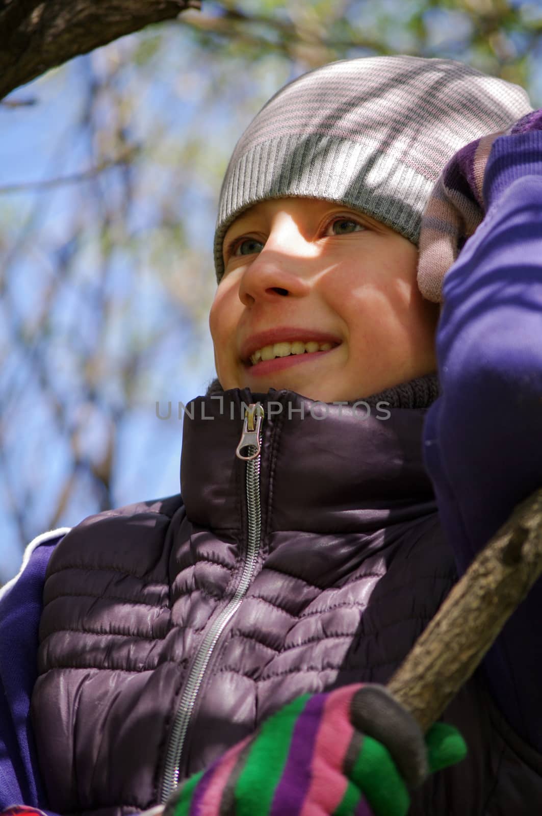 a Funny playful little girl climbing on a tree in the park. children outdoors. vacation in the spring park, closeup potrait.
