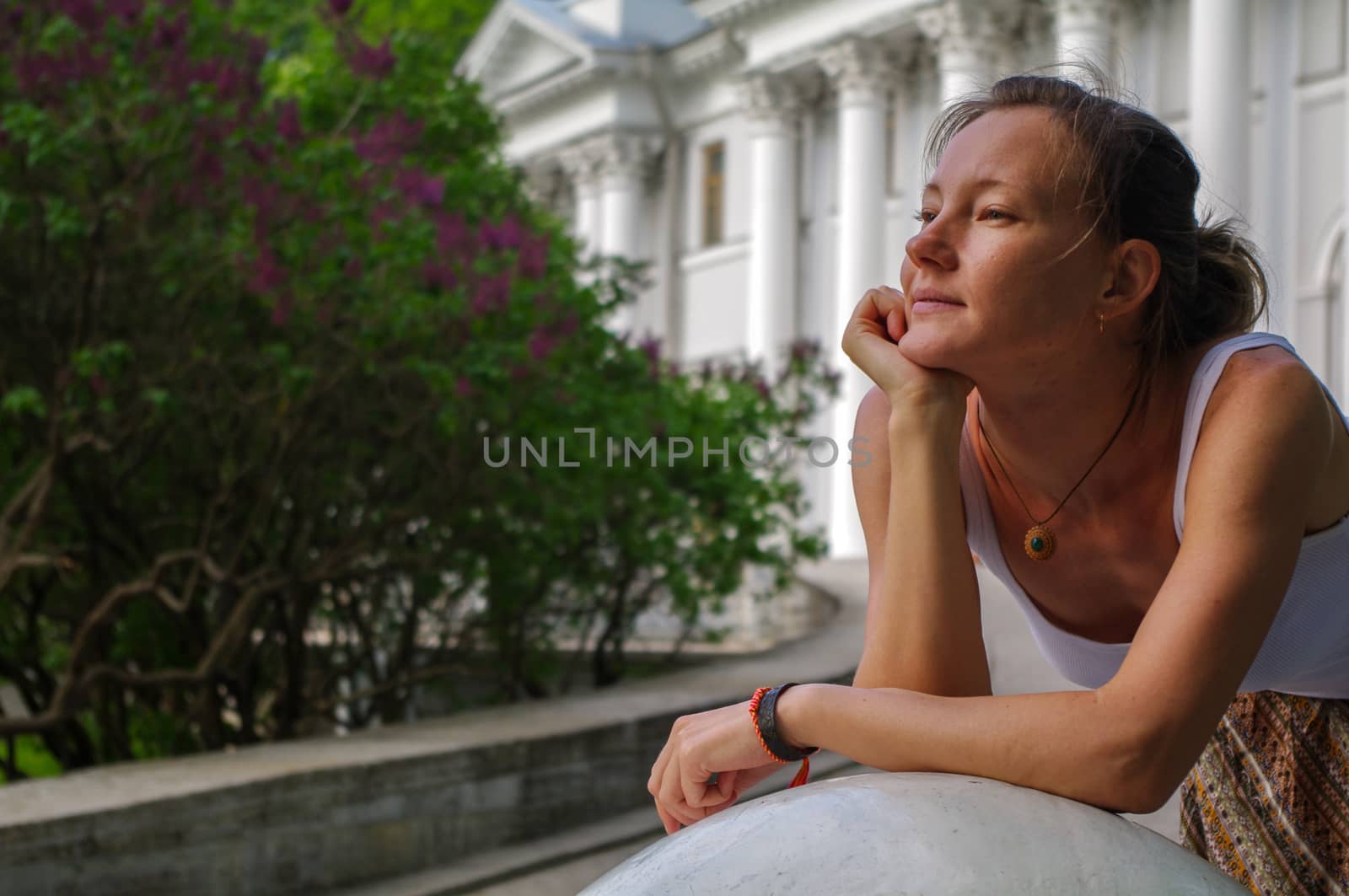 a portrait of young charming relaxing brunette woman with head laid on her arms at summer green park.