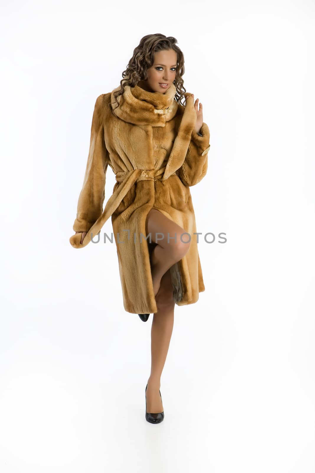 Young attractive woman in a fur coat on an isolated studio background