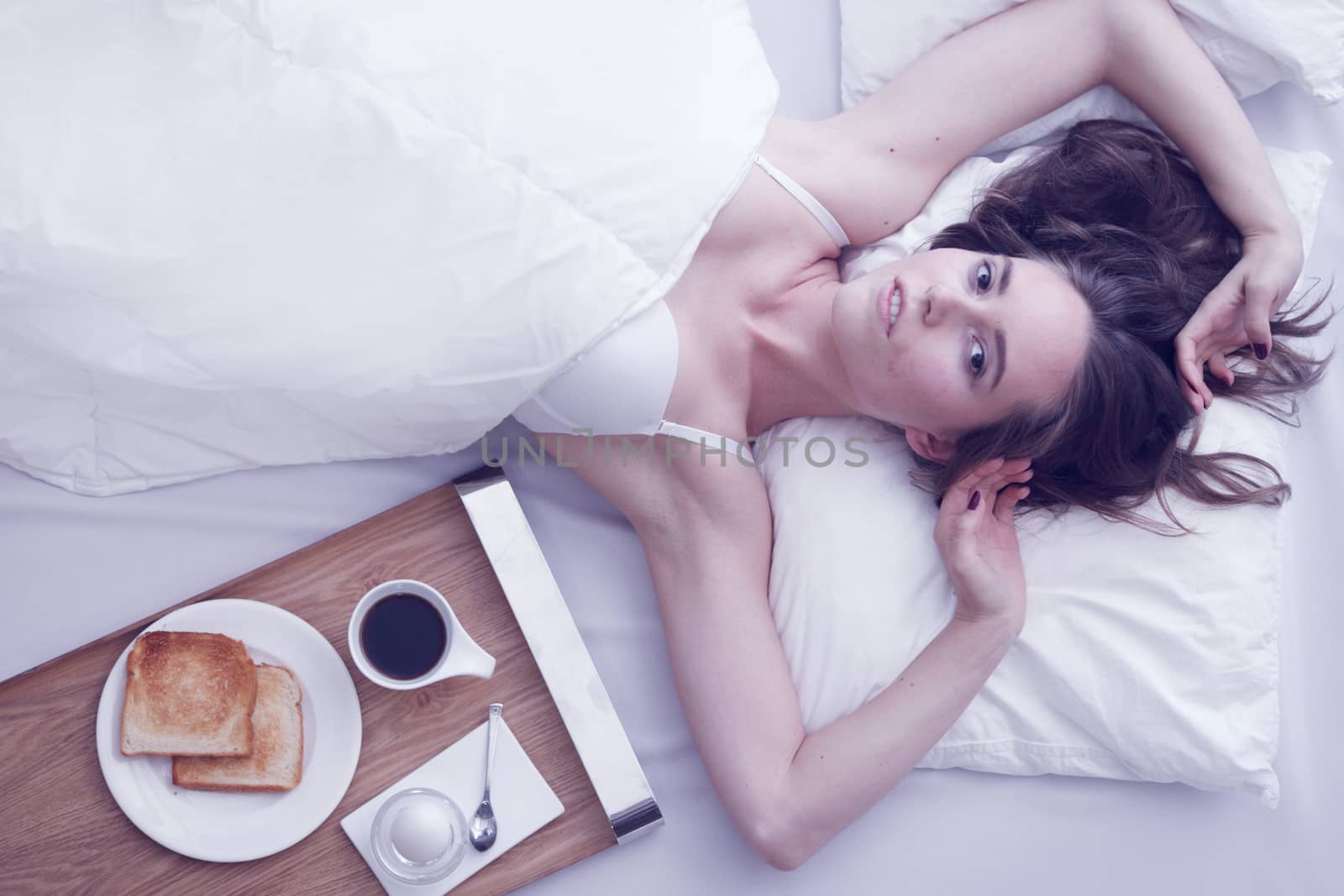 Beautiful young woman having breakfast in bed