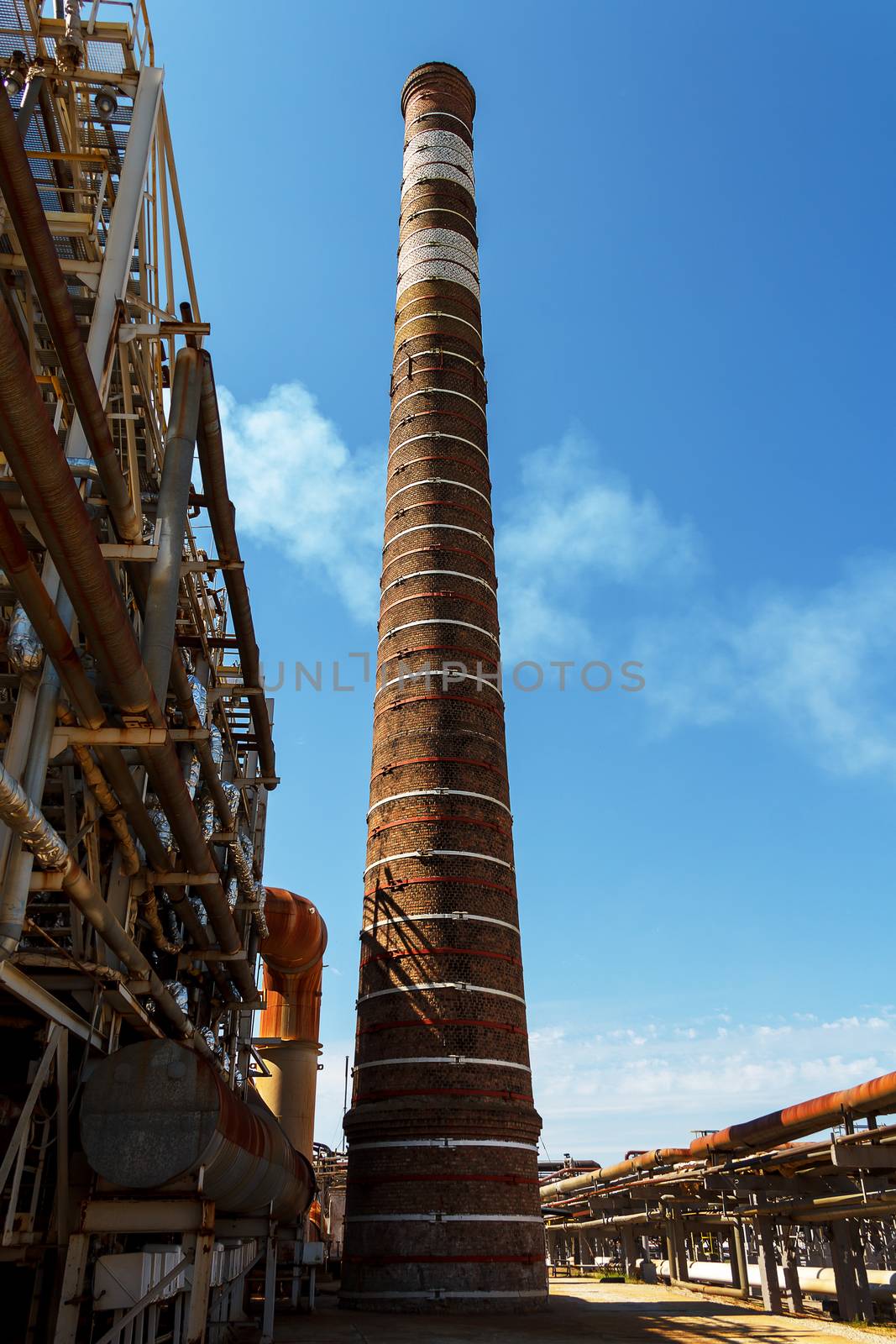 Tall chimney on fuel refinery factory by Julialine