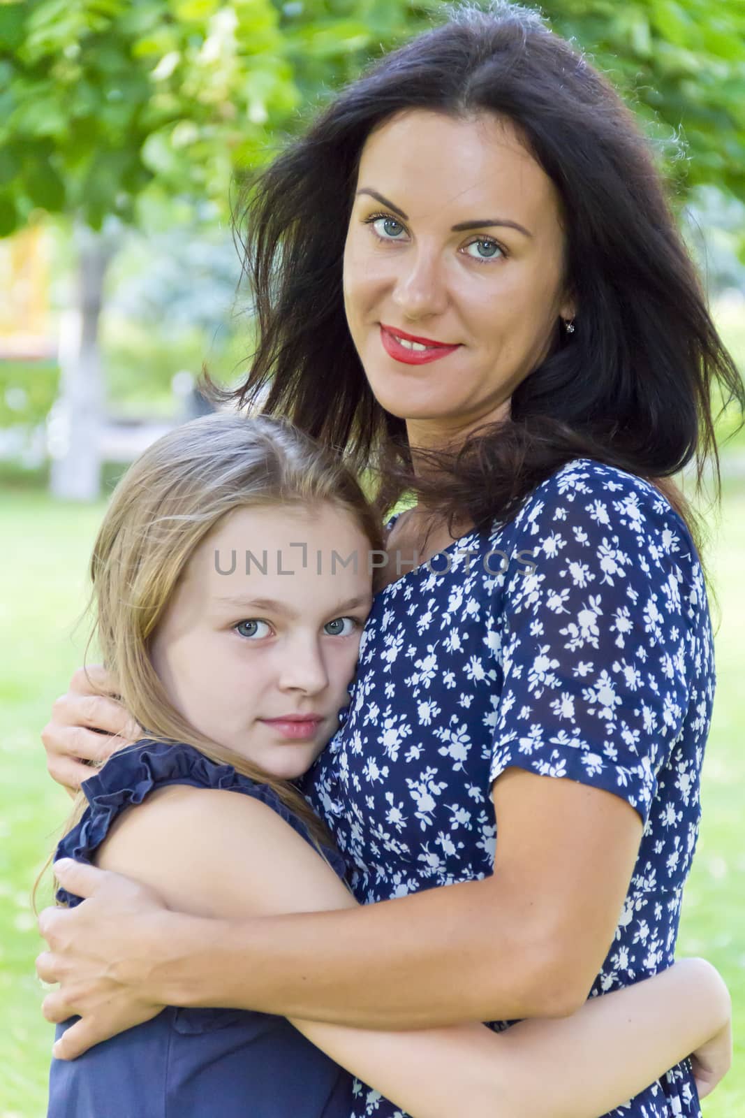 Embracing mother and daughter in summer on green background