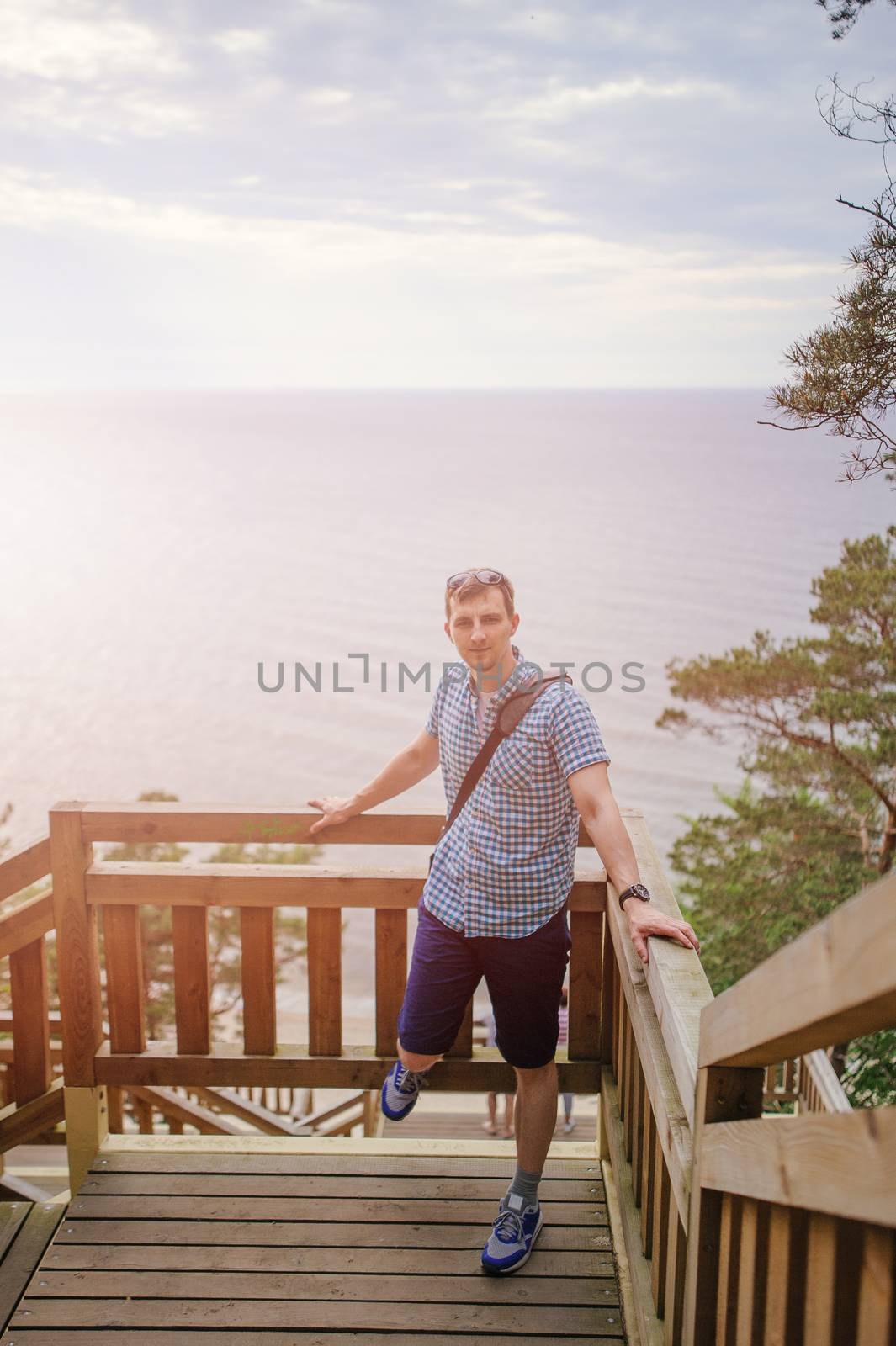 young man sitting on the wooden stairs in park and smiling