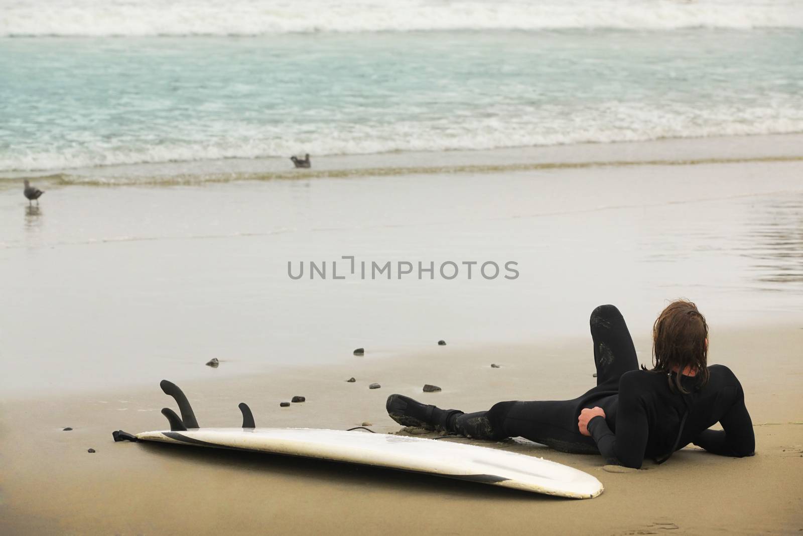 Surfer lying on a board resting on the beach