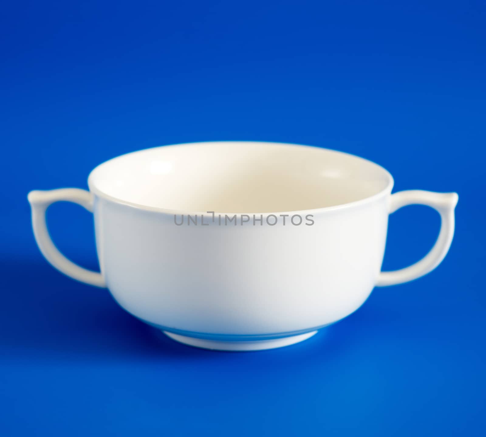 White cup of soup on blue background by olgavolodina