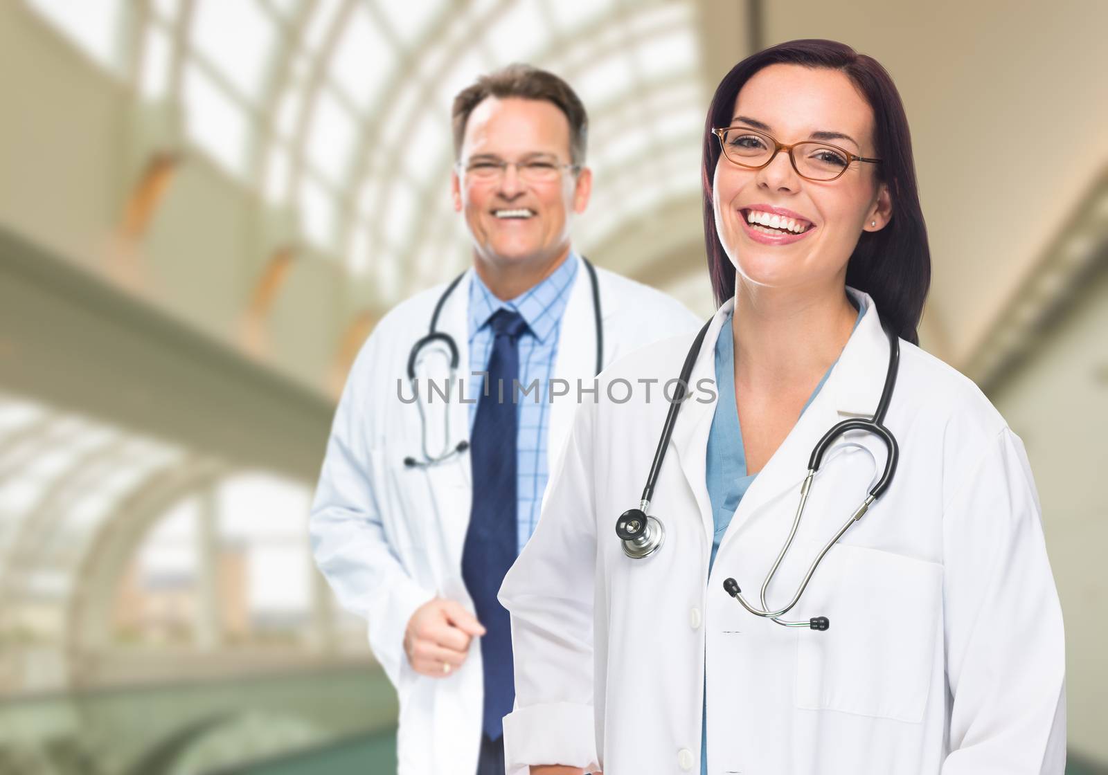 Two Male and Female Doctors or Nurses Standing Inside Hospital Building.