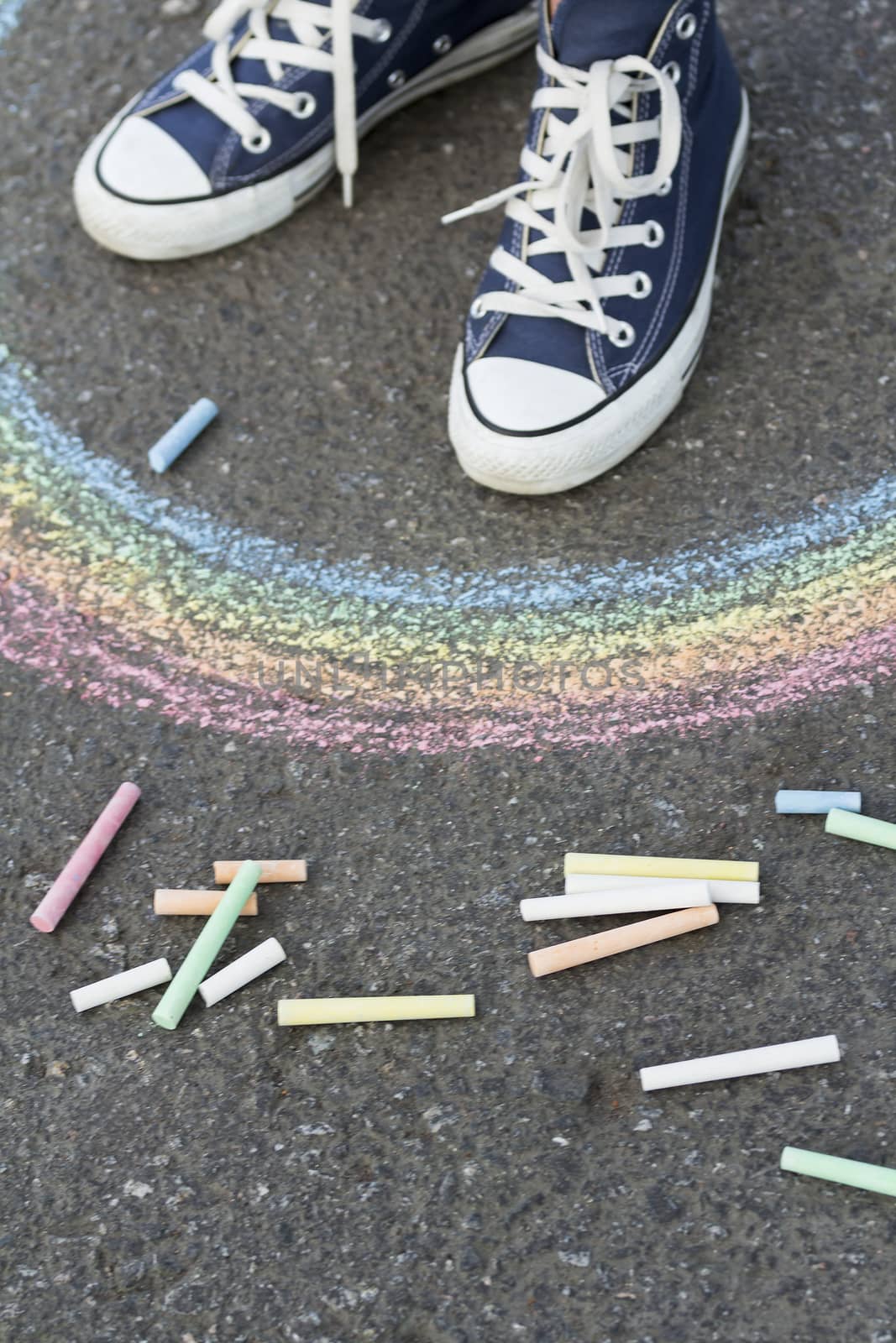 Feet in sneakers are on asphalt before drawn a rainbow