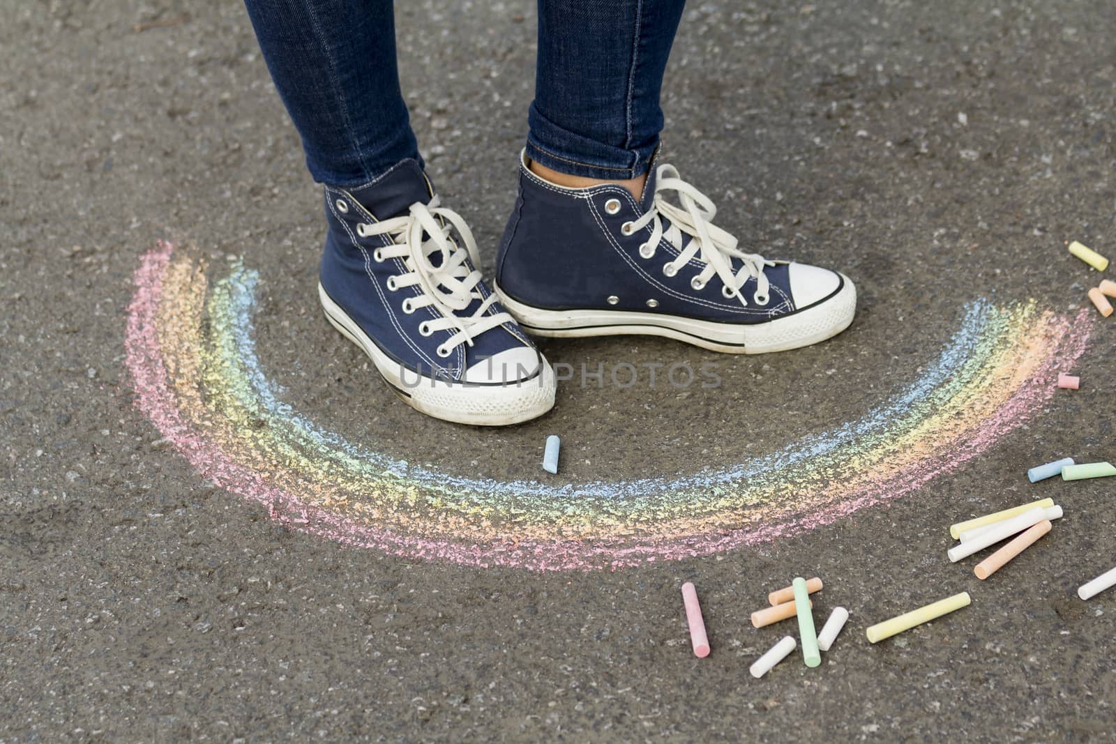 Feet in sneakers are on the pavement next to the picture of the Rainbow