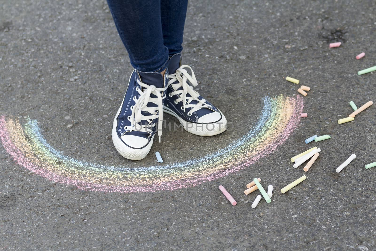 Feet in sneakers are on the pavement next to the picture of the Rainbow