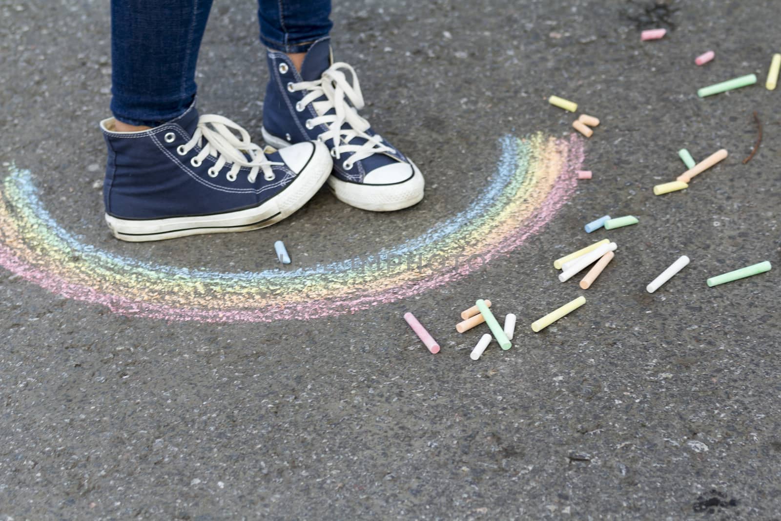 Feet in sneakers are on the pavement next to the picture of the Rainbow