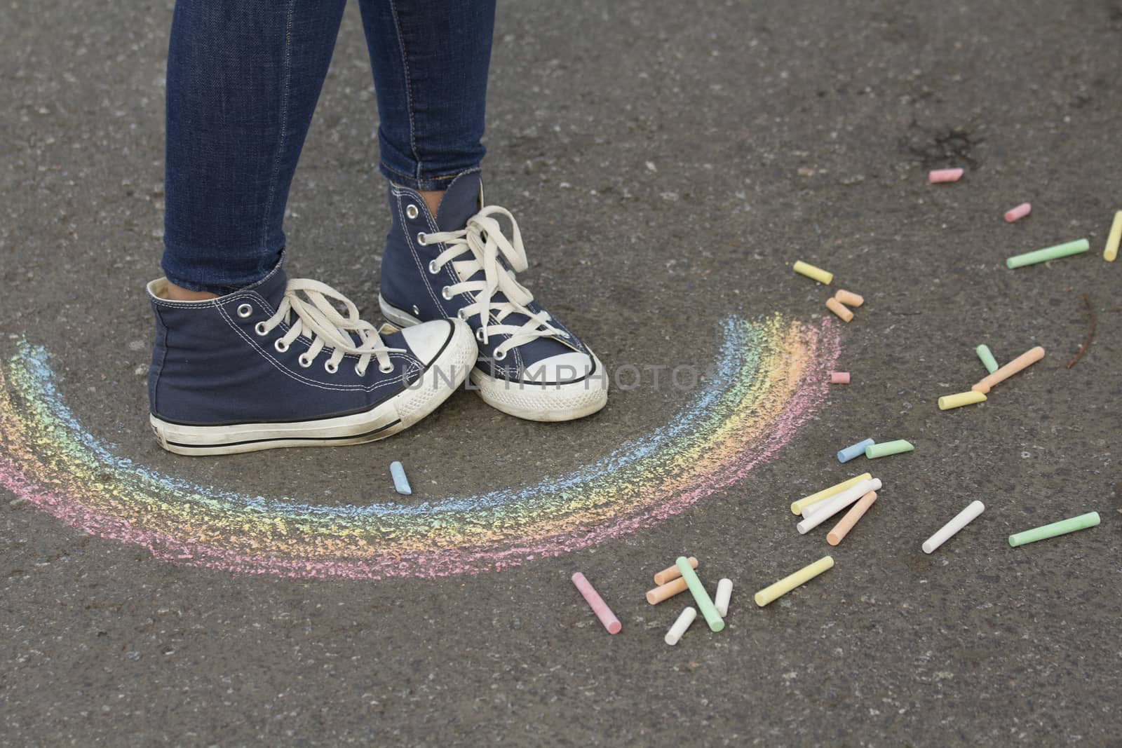 Feet in sneakers are on the pavement next to the picture of the Rainbow