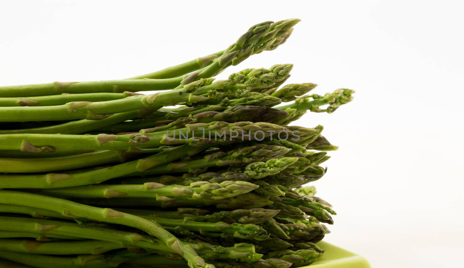 Asparagus spear on green plate with white background by fmcginn