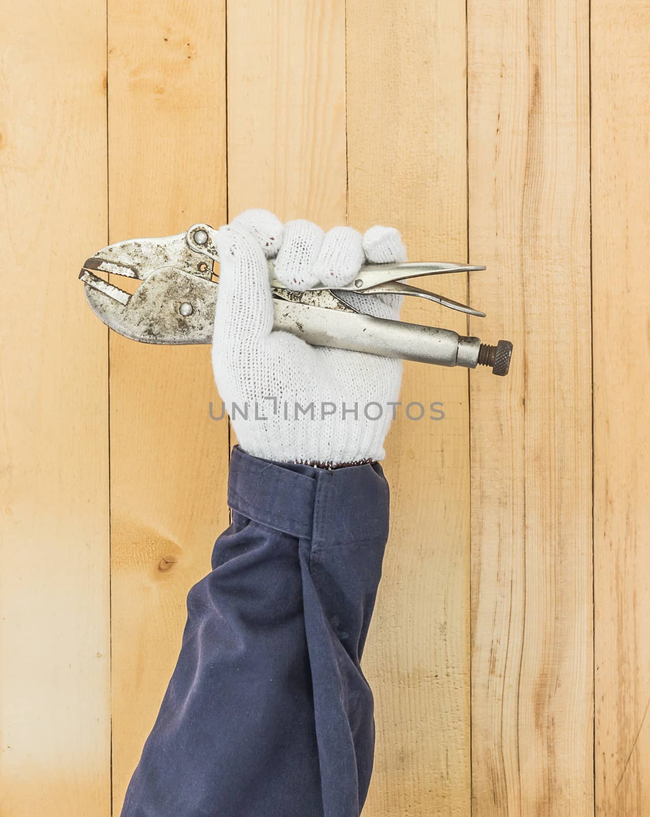 Working hand in glove holding a Adjustable wrench with wall wood background