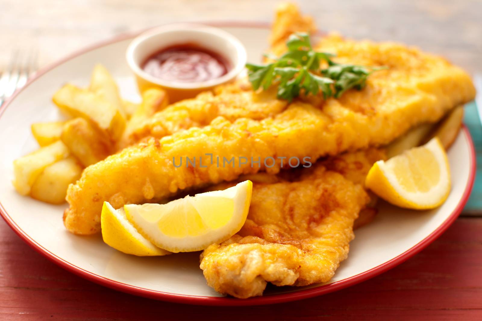 Two pieces of battered fish on a plate with chips