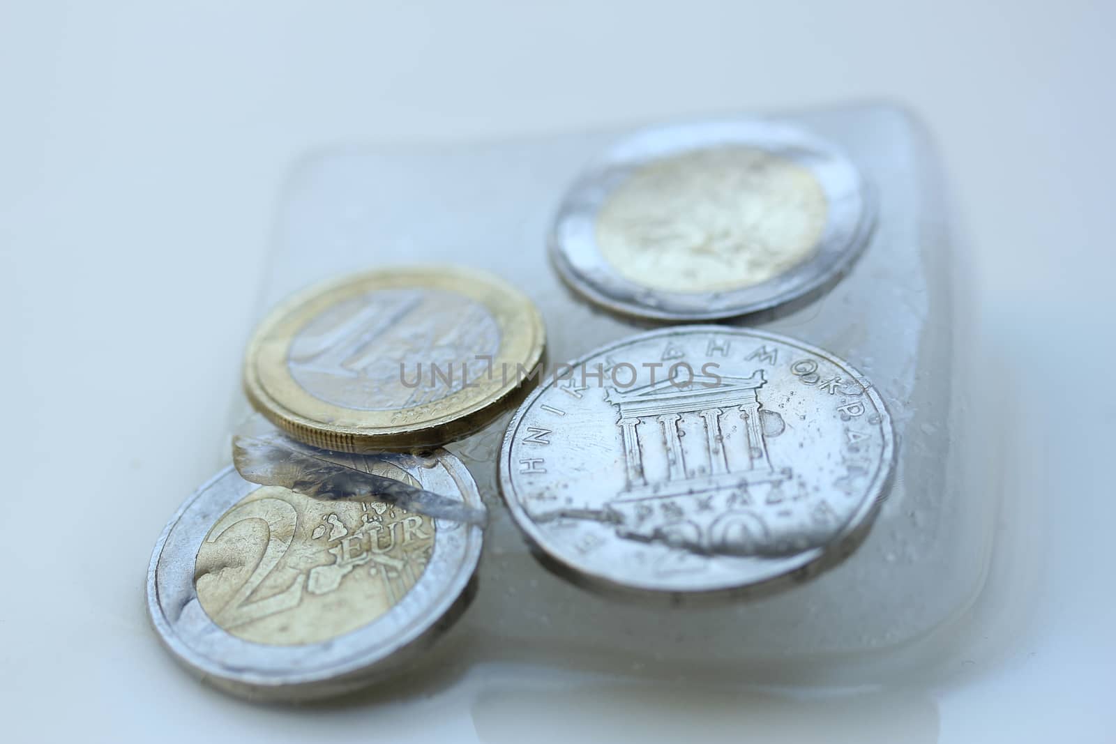 Frozen Assets: Greek euro and Drachme coins in ice