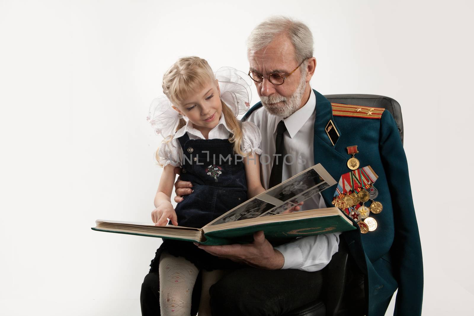 Old man in army uniform with rewards and beautiful little girl on isolated studio background