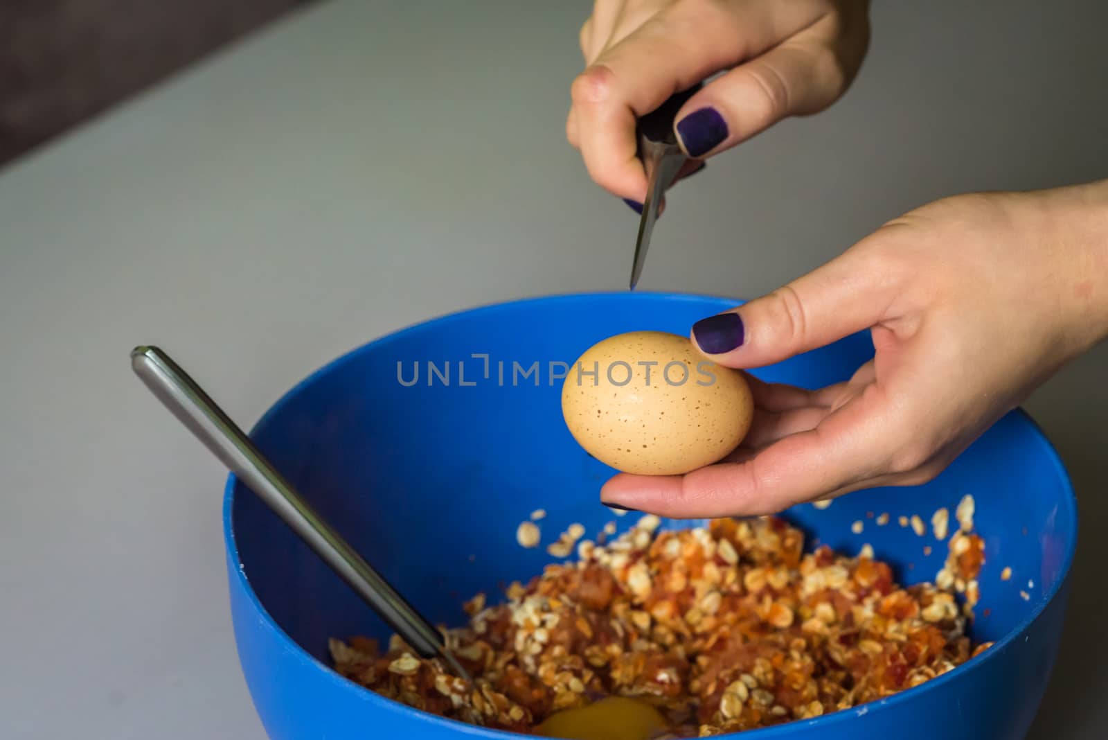 hand beats raw egg knife over a blue bowl