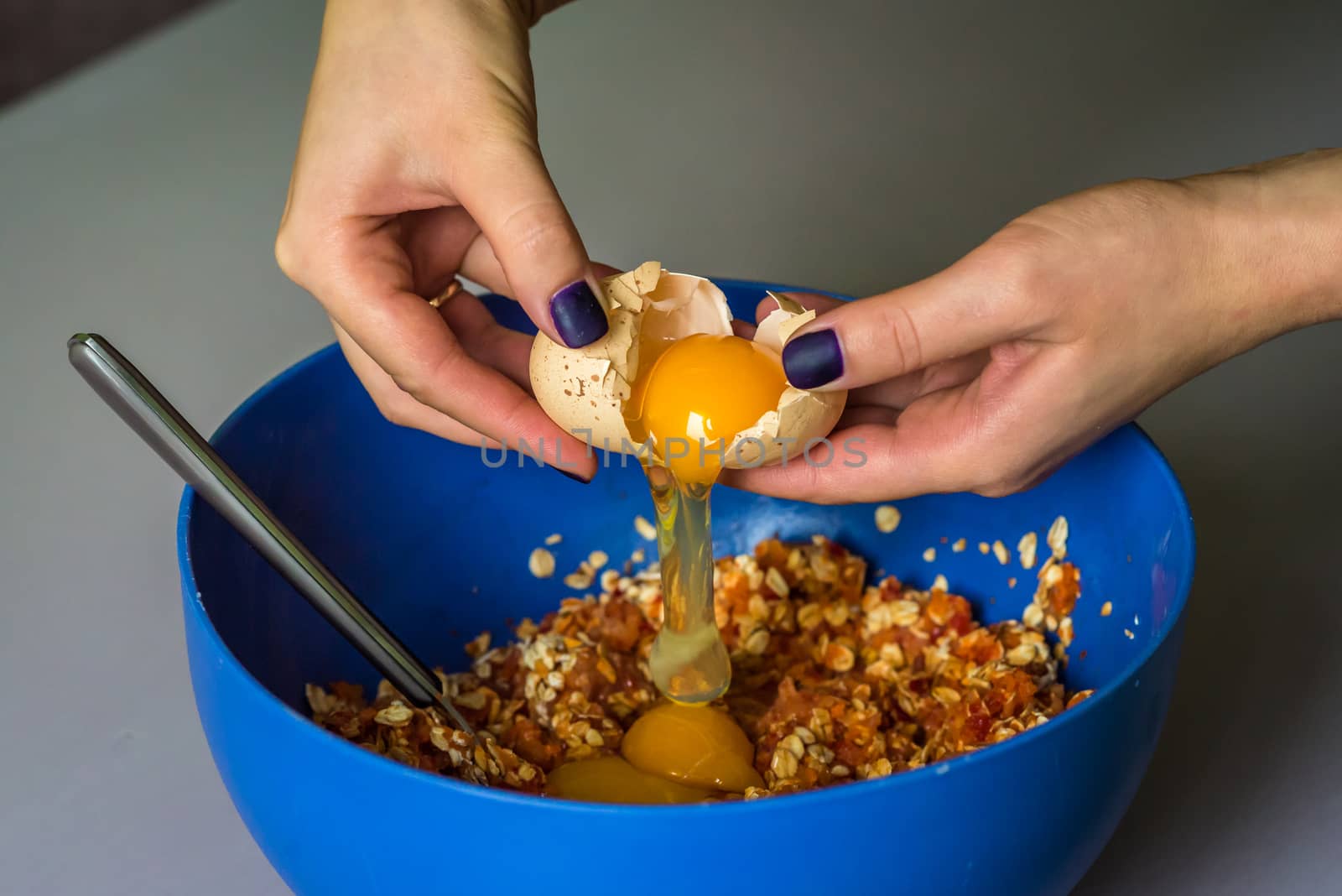 hand pours out raw egg of the shell in blue bowl