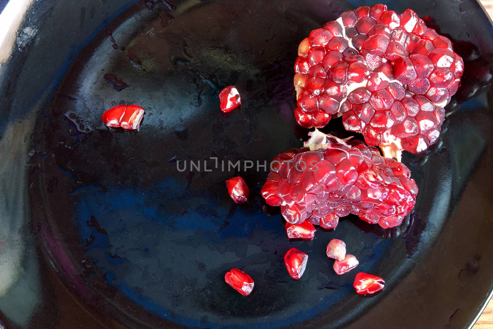 Carmine Pomegranate fruit cut dissect on black dish