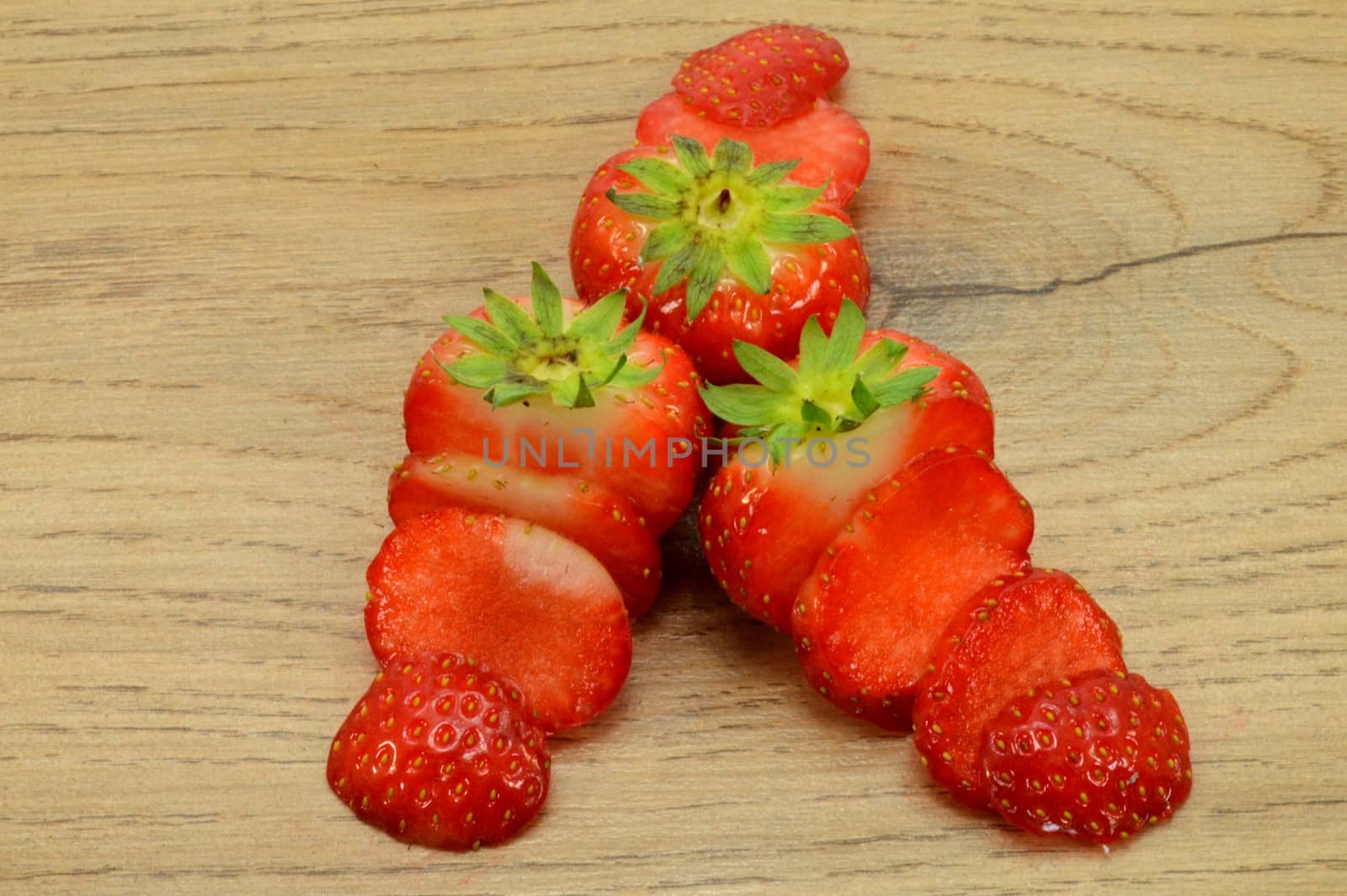 Strawberry trio cut into strips on a light wood background