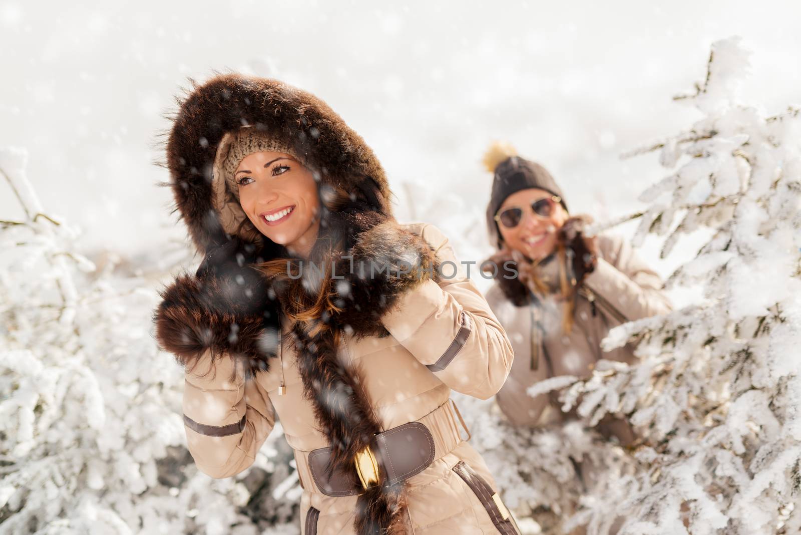 Two beautiful happy female friends taking a walk while its snowing.