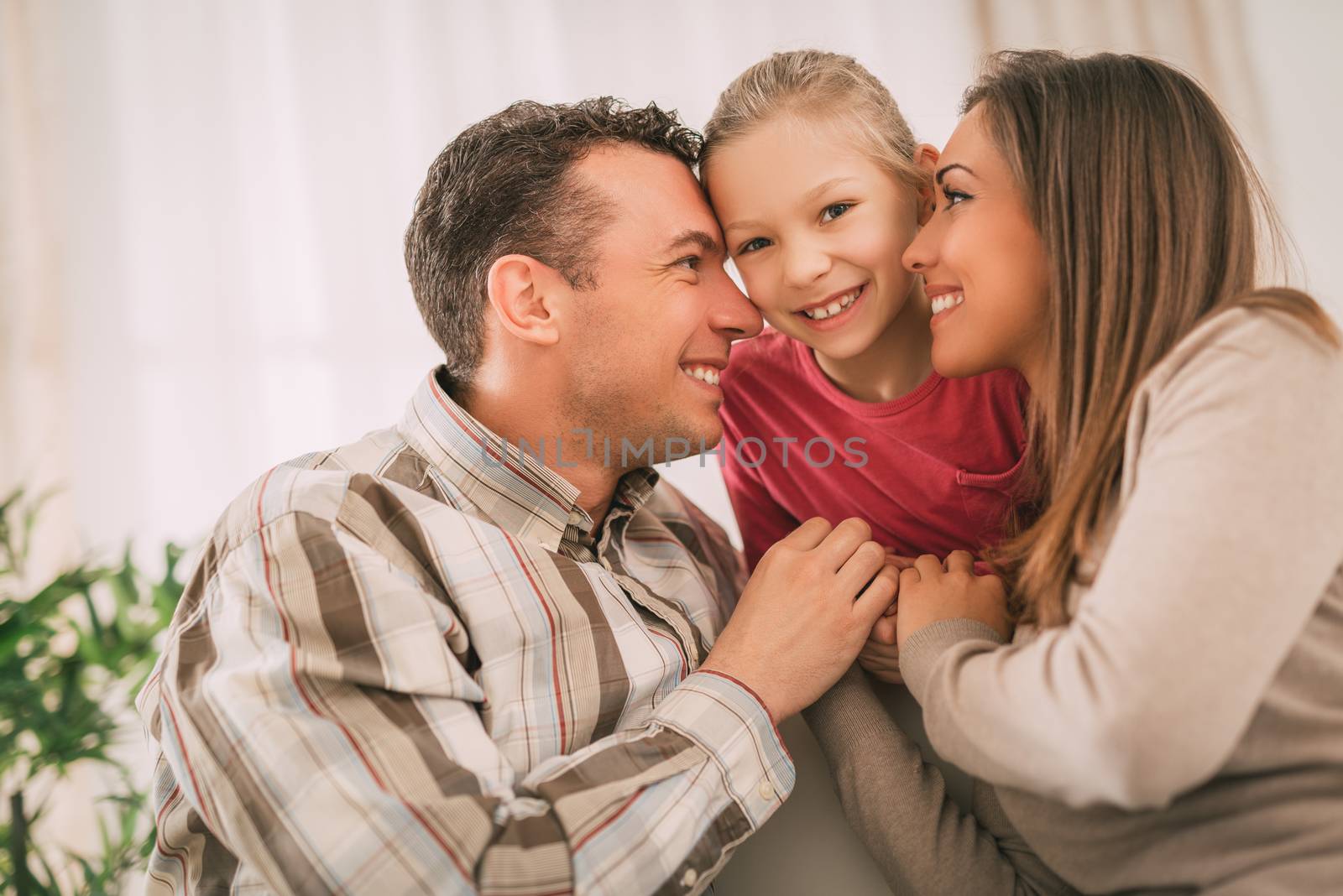 Beautiful young smiling family relaxing on sofa at living room.