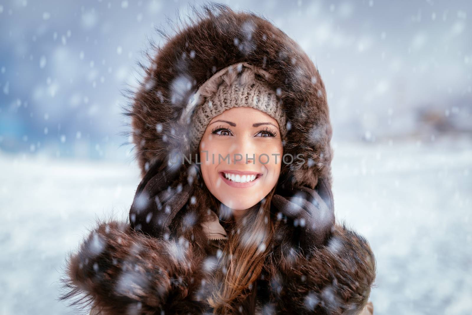 Portrait of a beautiful smiling girl outdoors while its snowing.