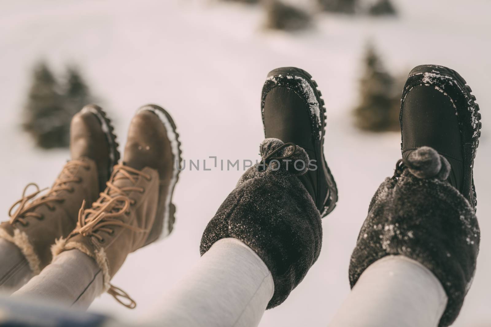 Close-up of a four unrecognizable female legs with boots on ski lift. Selective focus.