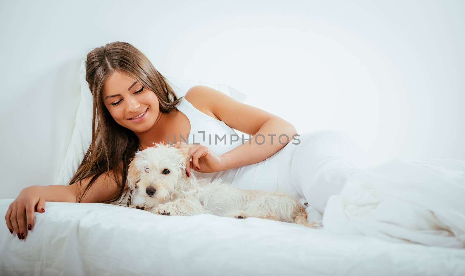 Beautiful young woman and her dog resting in bed in the morning.