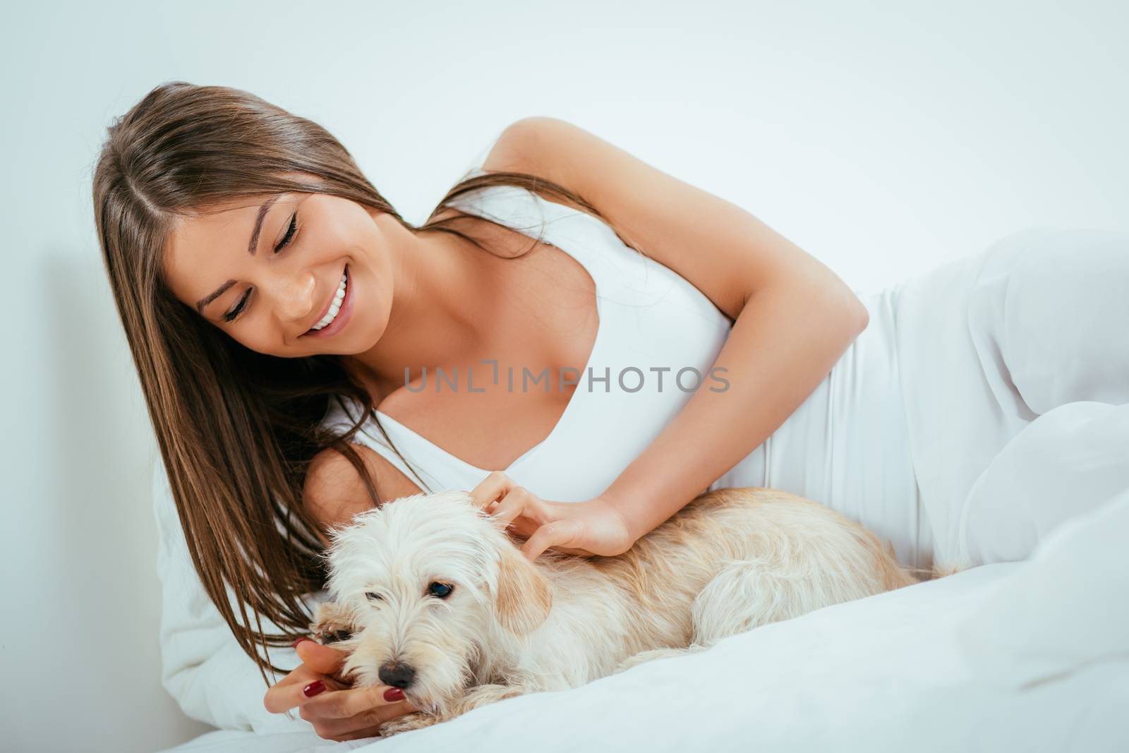 Beautiful young woman and her dog relaxing in bed in the morning.