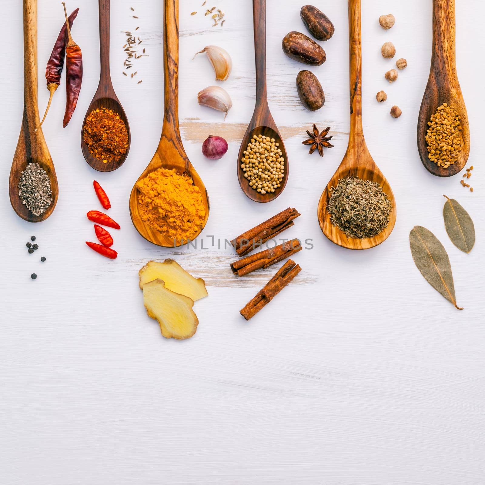 Various herbs and spices in wooden spoons. Flat lay of spices ingredients chilli ,pepper, garlic,dries thyme, cinnamon,star anise, nutmeg, shallot  ,bay leaves and fenugreek on wooden background.