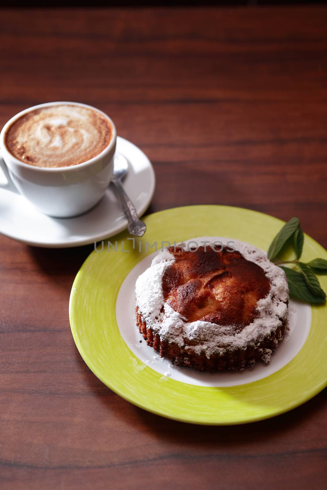 Cake on plate near cup of coffee on wooden table