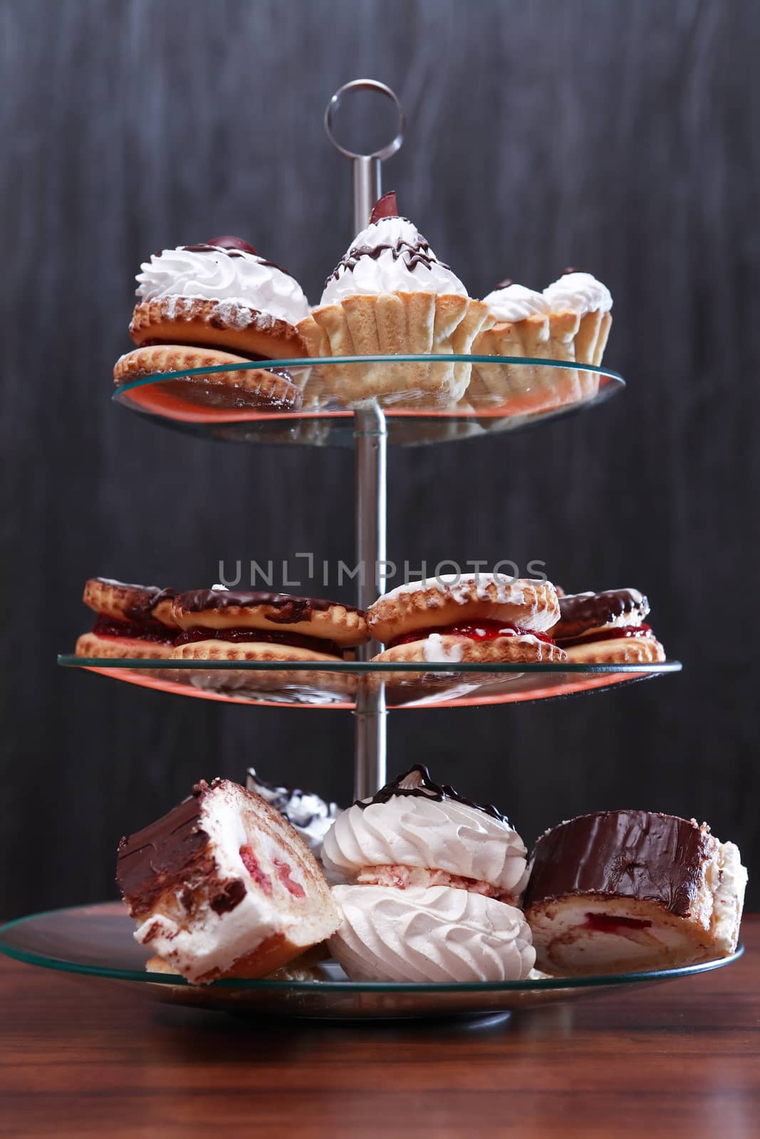 Set of various cakes on stand against dark background