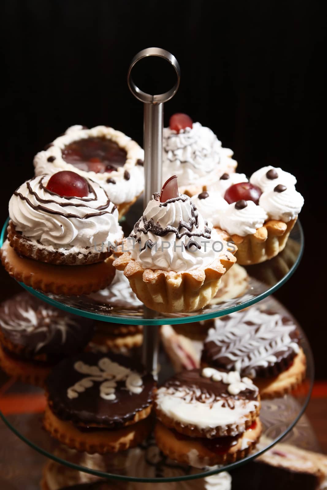 Set of various cakes on stand against dark background