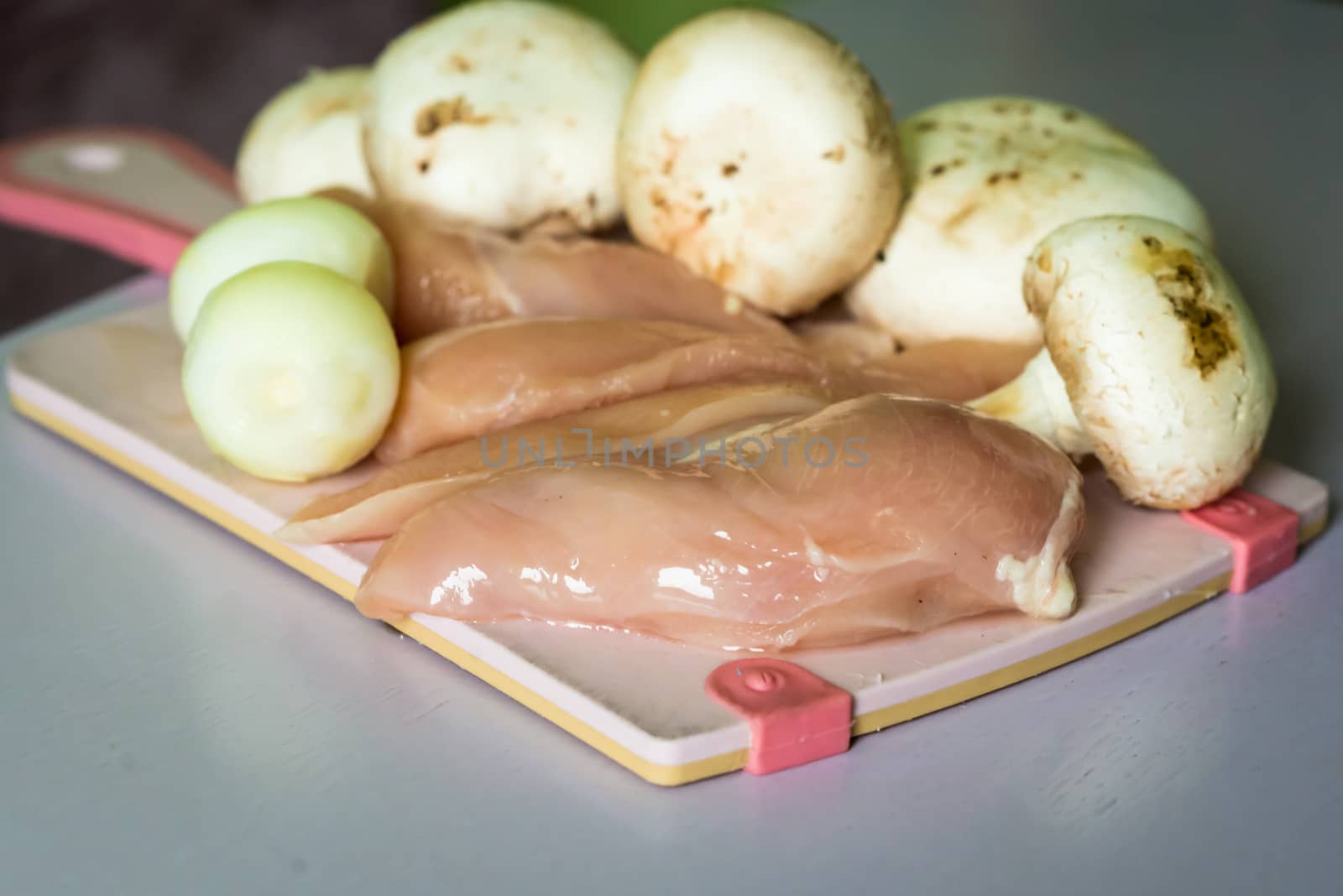 raw chicken meat and mushrooms on the board