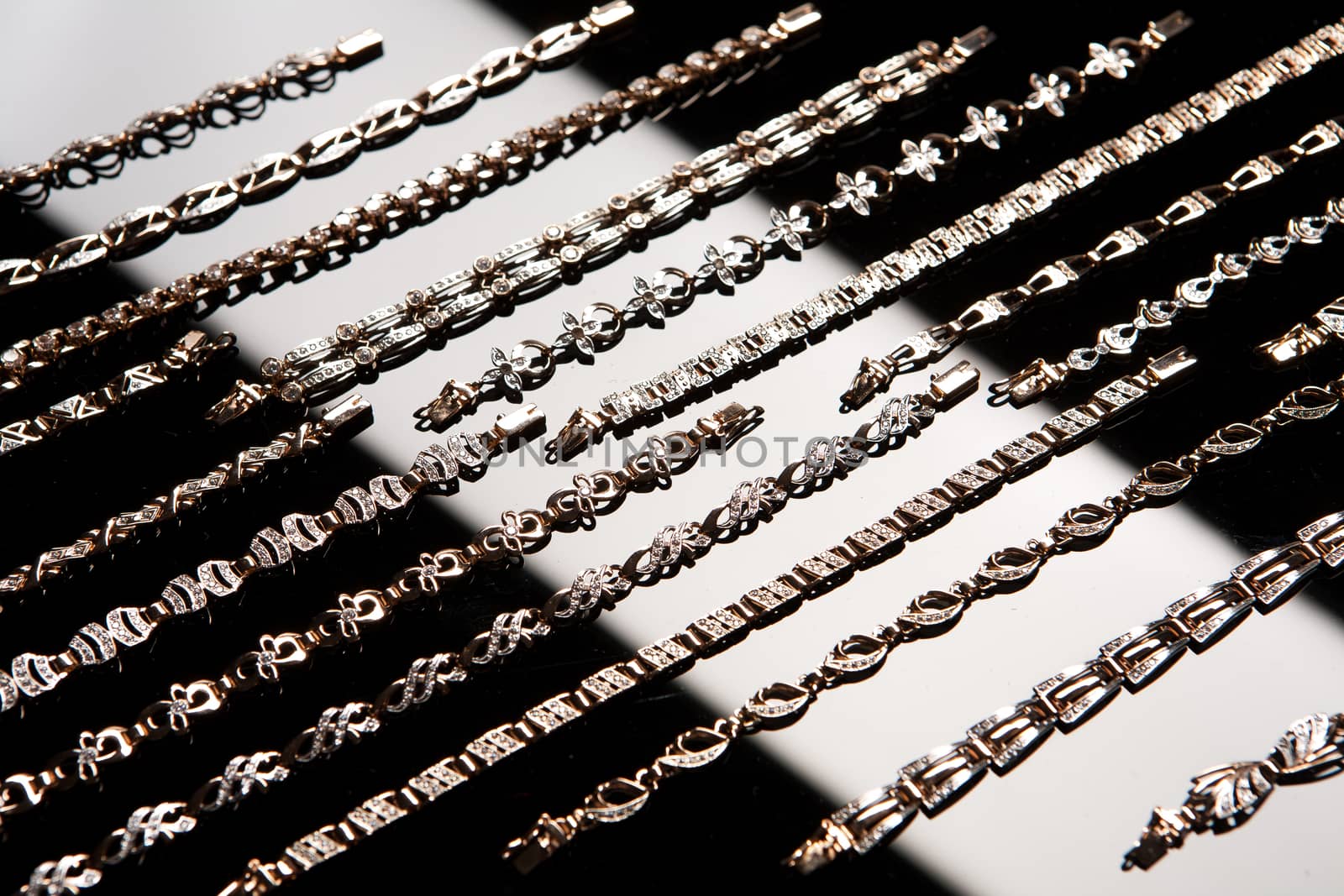 Golden bracelets on a black glass background with white highlight