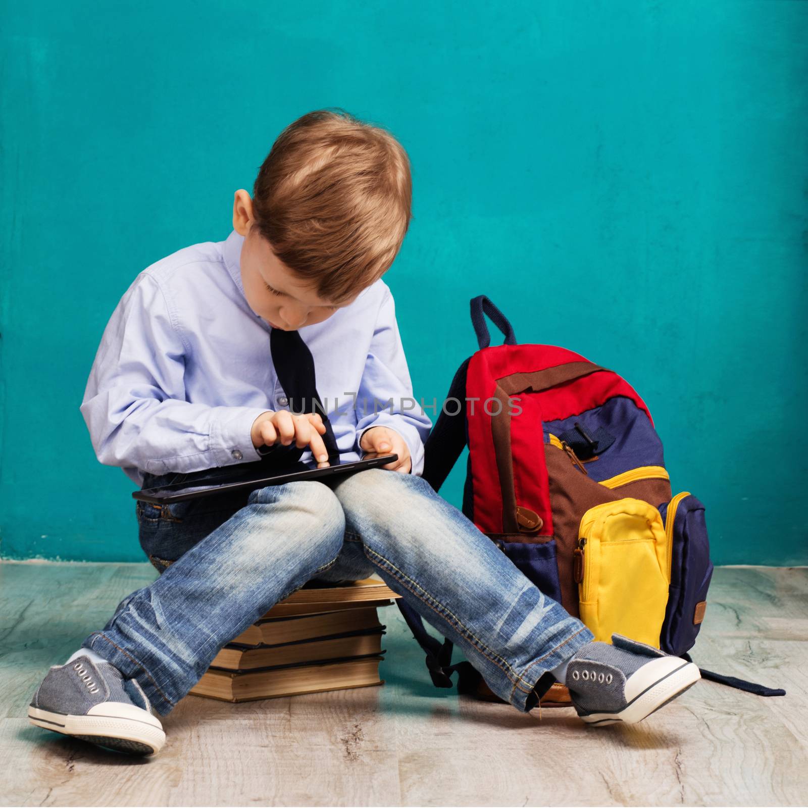 Cheerful little boy with big backpack holding digital tablet aga by natazhekova