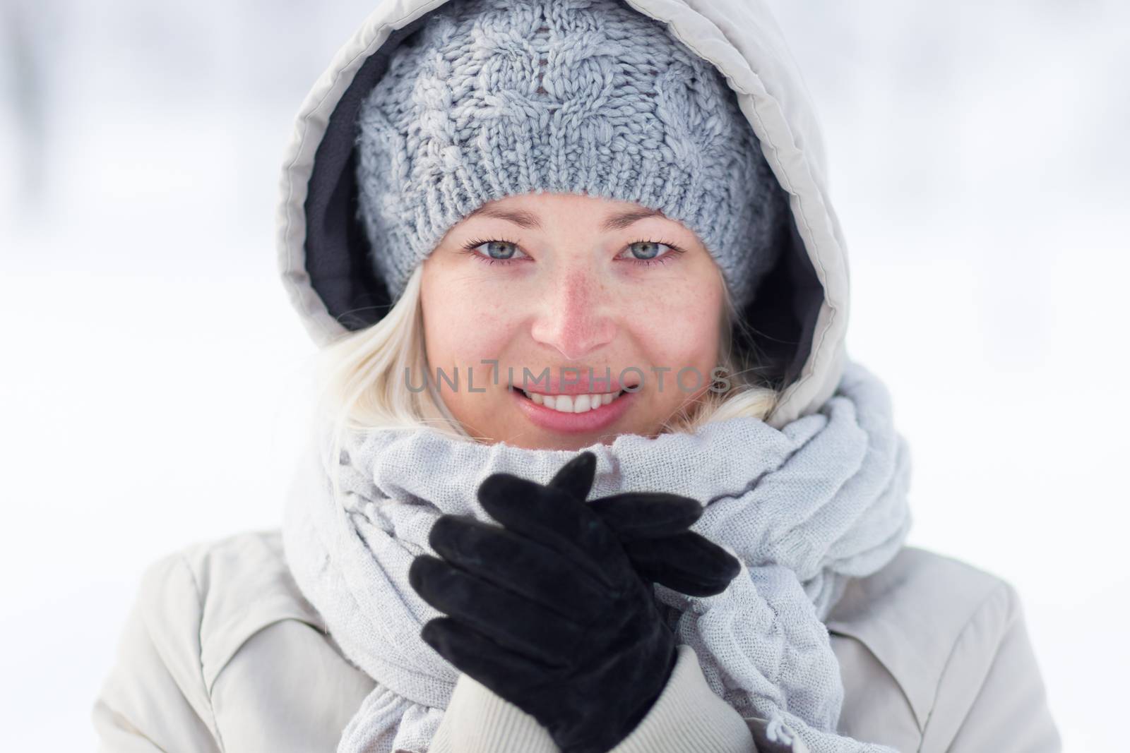 Girl wearing gloves, beeing cold outdoors in winter. Beautiful winter portrait of young woman in the winter snowy scenery.