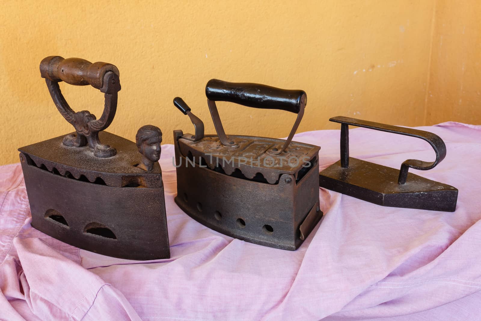 three old irons  made of cast-iron   on a shirt