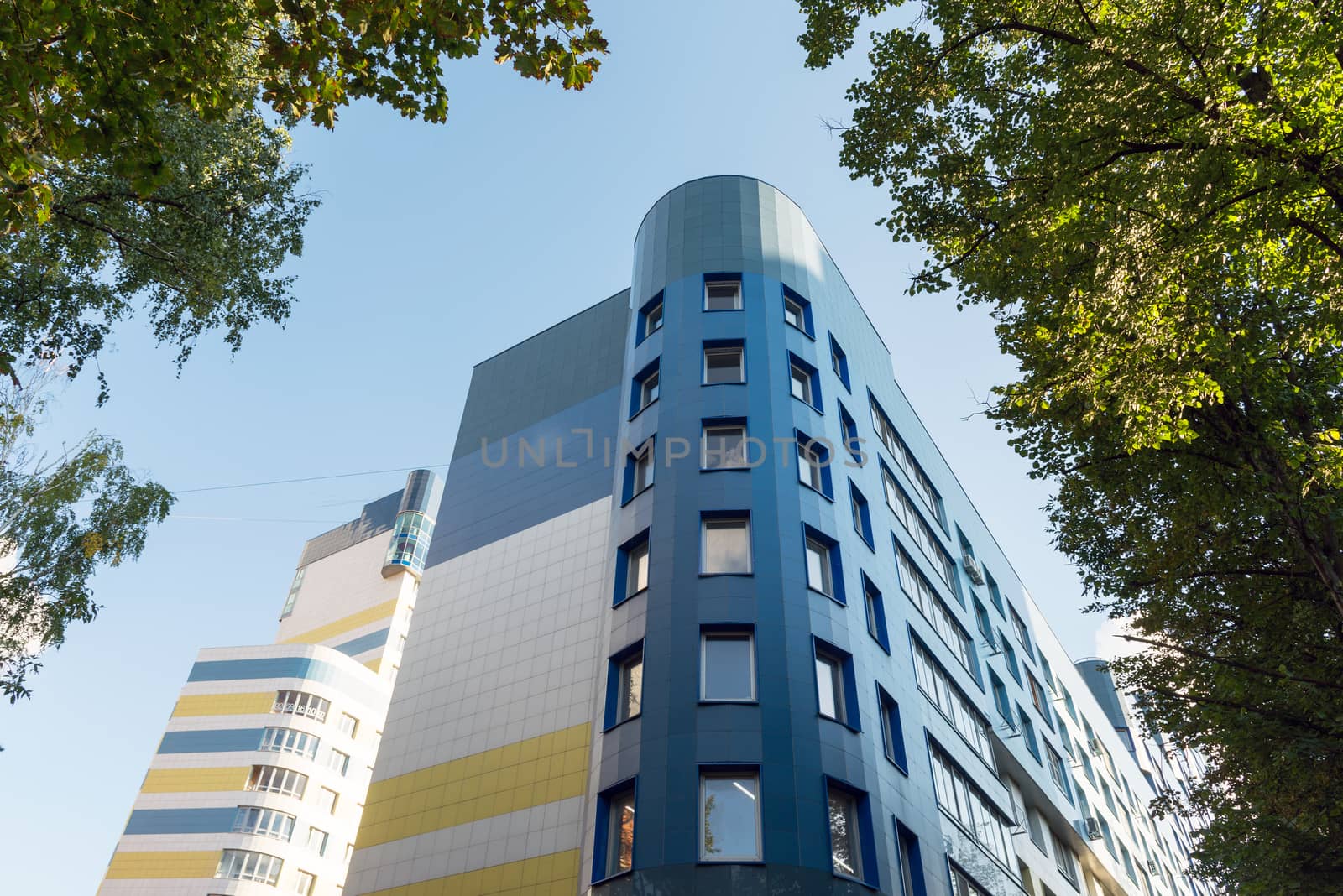 modern multi-storey residential building on background of blue sky by olgavolodina