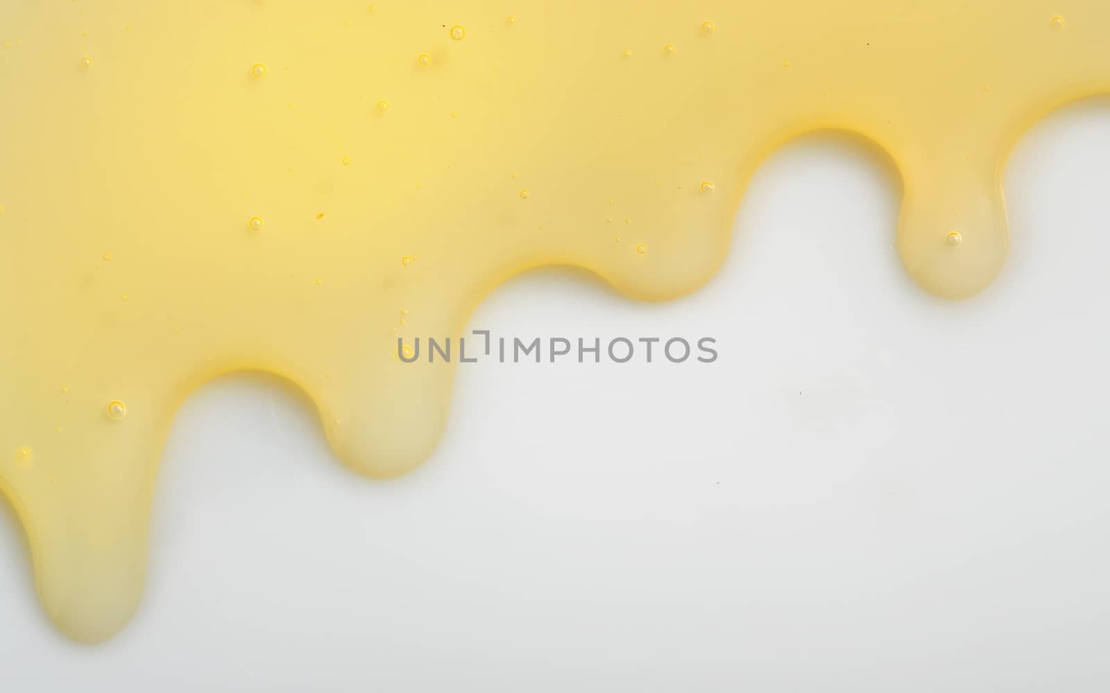 Honey liqiud flowing down on white background