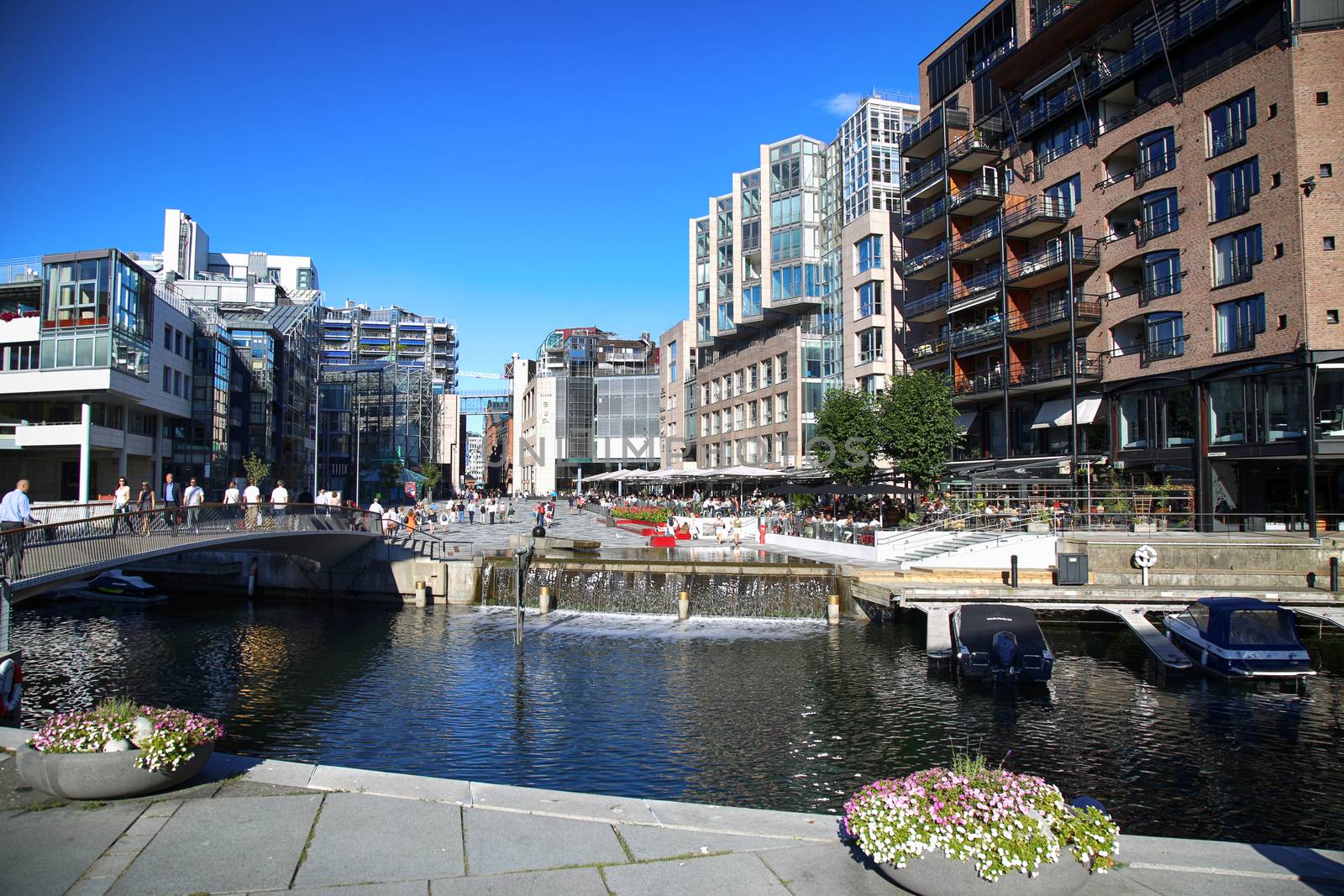 OSLO, NORWAY – AUGUST 17, 2016: People walking on wonderful modern residential district Aker Brygge with lux apartments, shopping, culture and restaurants in Oslo, Norway on August 17,2016.